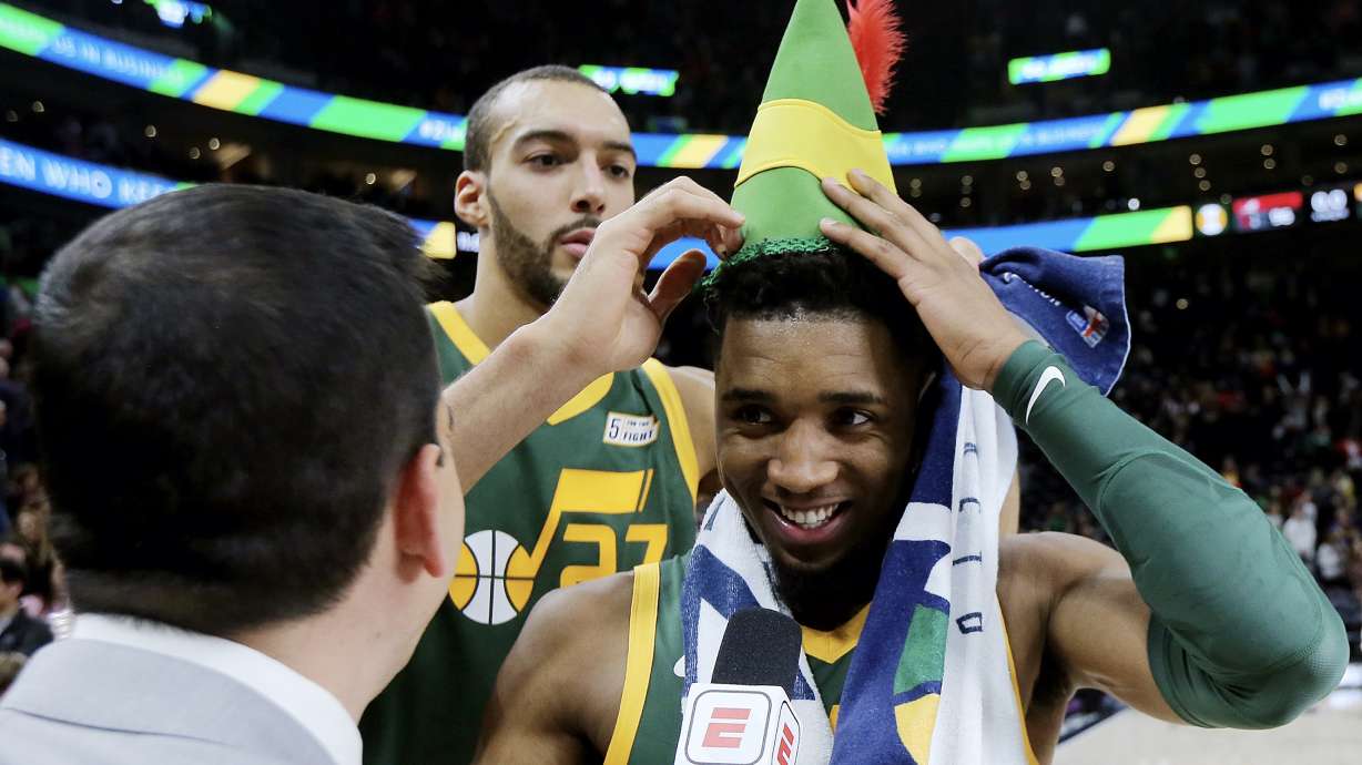 Utah Jazz center Rudy Gobert (27) puts an Elf hat on Utah Jazz guard Donovan Mitchell (45) during a postgame interview as the Utah Jazz defeat the Portland Trail Blazers in an NBA basketball game at Vivint Arena in Salt Lake City on Tuesday, Dec. 25, 2018. Jazz won 117-96.