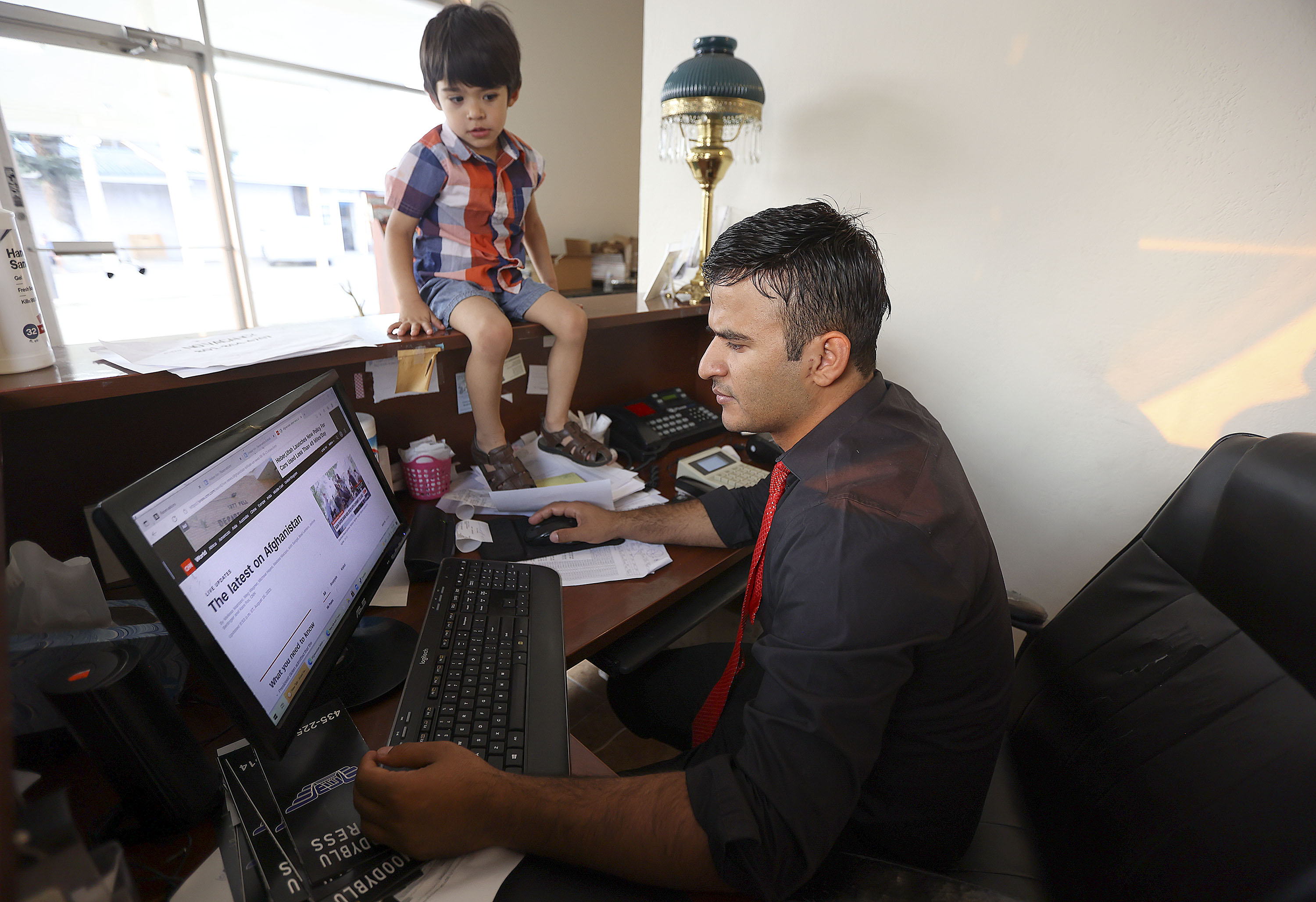 Wisal Kamyar, who used to be an interpreter for the U.S. Army in Afghanistan, reads a news report on Afghanistan as his son, Hooman Kamyar, watches at the Heber Inn, where Kamyar works, in Heber City on Monday.