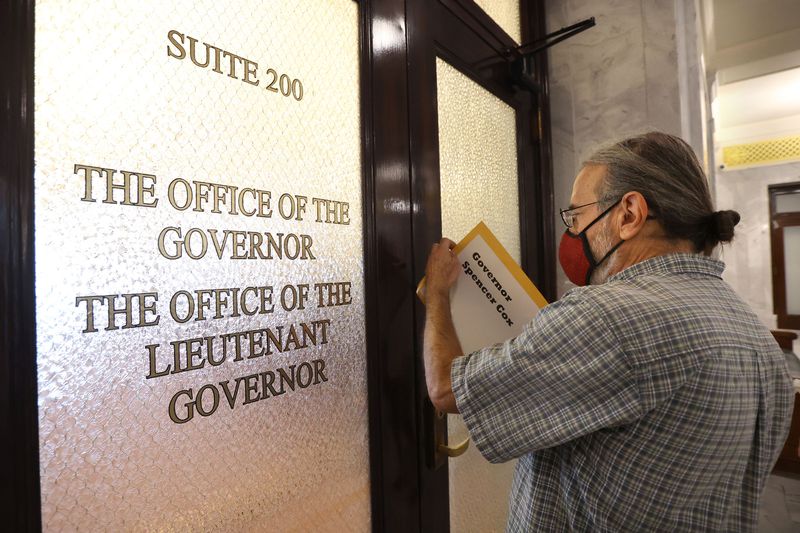 Jim Catano slides a copy of the Utah Clean Infrastructure Coalition report through the doors to the governor’s
office at the Capitol in Salt Lake City on Tuesday after a staffer said she could not accept packages or mail for the
governor’s office. The report alleges Utah’s Permanent Community
Impact Fund Board used more than $109 million in public funds for
fossil fuel projects, in violation of the federal Mineral Leasing
Act.