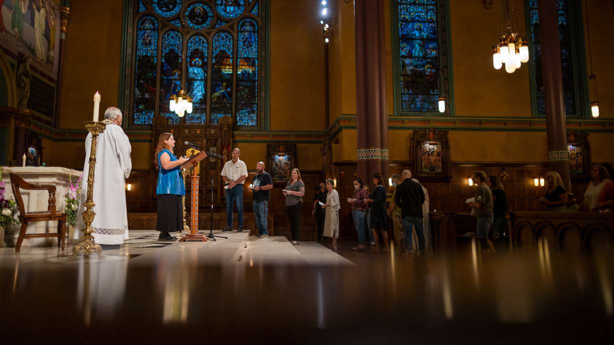 The Very Rev. Martin Diaz listens as Wendy Garvin, executive director of Unsheltered Utah, reads the name of someone who died and whose remains were never claimed during a service at The Cathedral of the Madeleine in Salt Lake City on Tuesday.