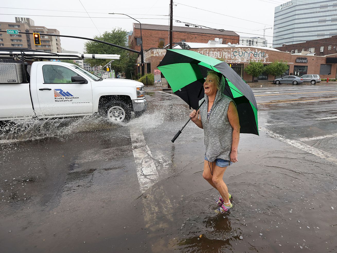 Jennifer Jensen walks through a puddle on the corner 300 East and 300 South on her way to tai chi in Salt Lake City on
Wednesday. As rain sweeps across much of Utah, the big question on the minds of many residents is how much does this moisture help in the face of the unrelenting drought.