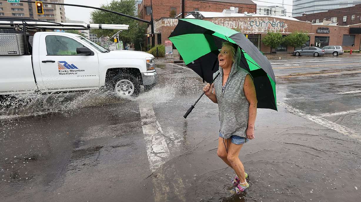 Jennifer Jensen walks through a puddle on the corner 300 East and 300 South on her way to tai chi in Salt Lake City on
Wednesday. As rain sweeps across much of Utah, the big question on the minds of many residents is how much does this moisture help in the face of the unrelenting drought.