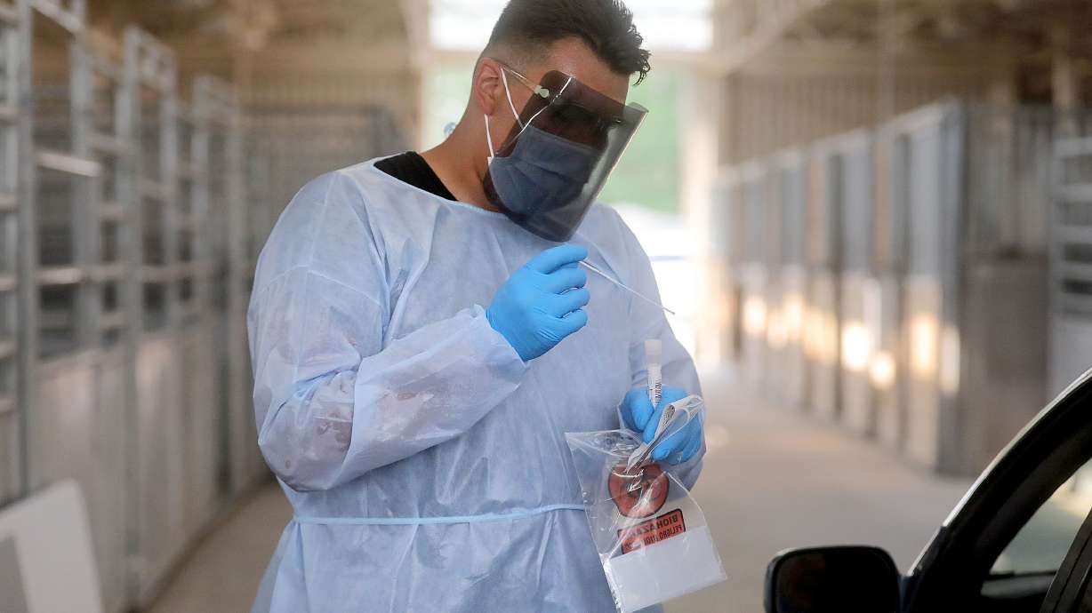 Xander Yazzie, a Utah National Guard service member, performs a COVID-10 test at the Utah State Fairpark in Salt Lake City on Monday. Utah health officials reported 1,488 new COVID-19 cases and 12 additional deaths on Wednesday.