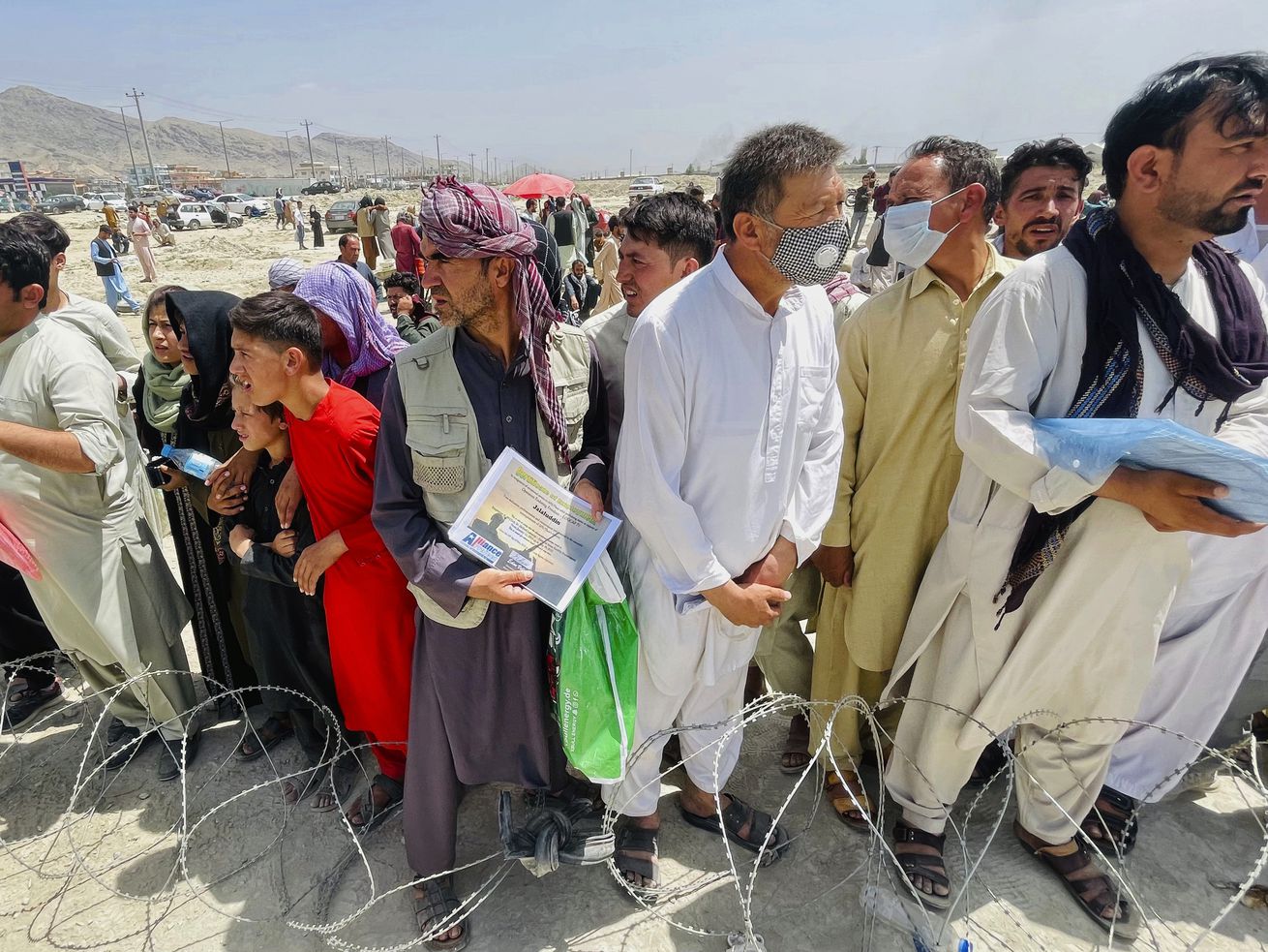 A man holds a certificate acknowledging his work for Americans as hundreds of people gather outside the international airport in Kabul, Afghanistan, on Tuesday. Utah’s two senators say their joint constituent office is working around the clock to help the evacuation of U.S. and Afghan citizens from Afghanistan amid the Taliban takeover.
