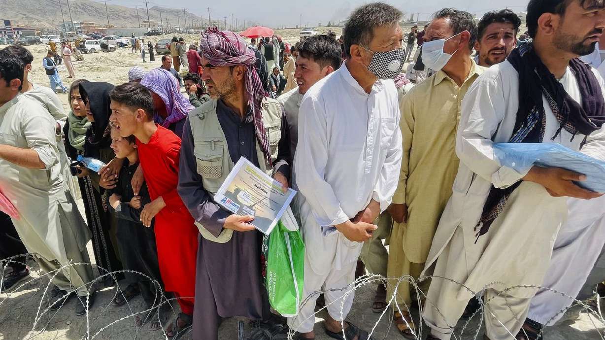 A man holds a certificate acknowledging his work for Americans as hundreds of people gather outside the international airport in Kabul, Afghanistan, on Tuesday. Utah’s two senators say their joint constituent office is working around the clock to help the evacuation of U.S. and Afghan citizens from Afghanistan amid the Taliban takeover.