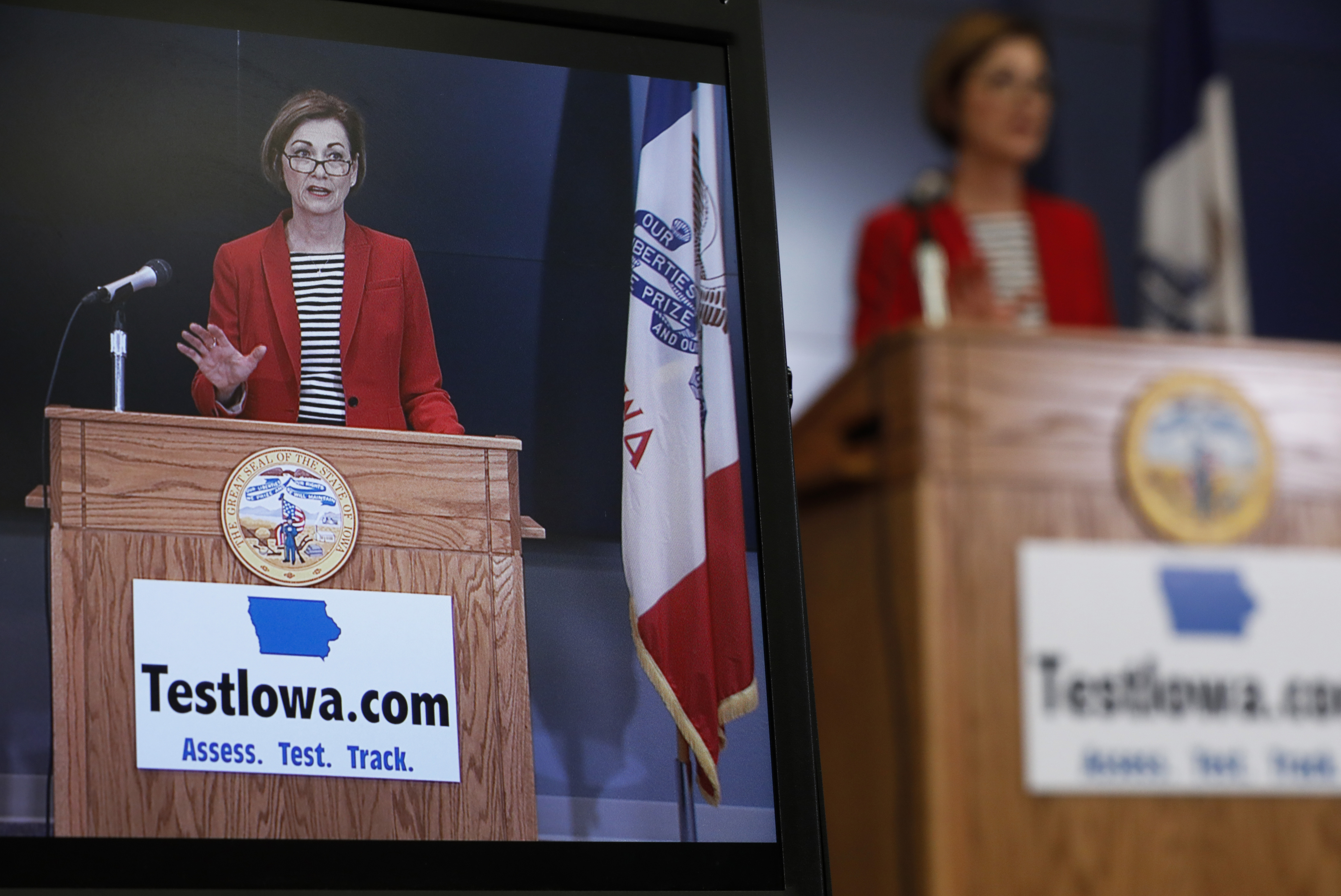 Iowa Gov. Kim Reynolds is seen on a monitor during a news conference at the State Emergency Operations Center, in Johnston, Iowa, on April 30, 2020. A new lawsuit contends that Reynolds' office is illegally delaying the release of public records related to the state's $26 million, no-bid coronavirus testing contract. 