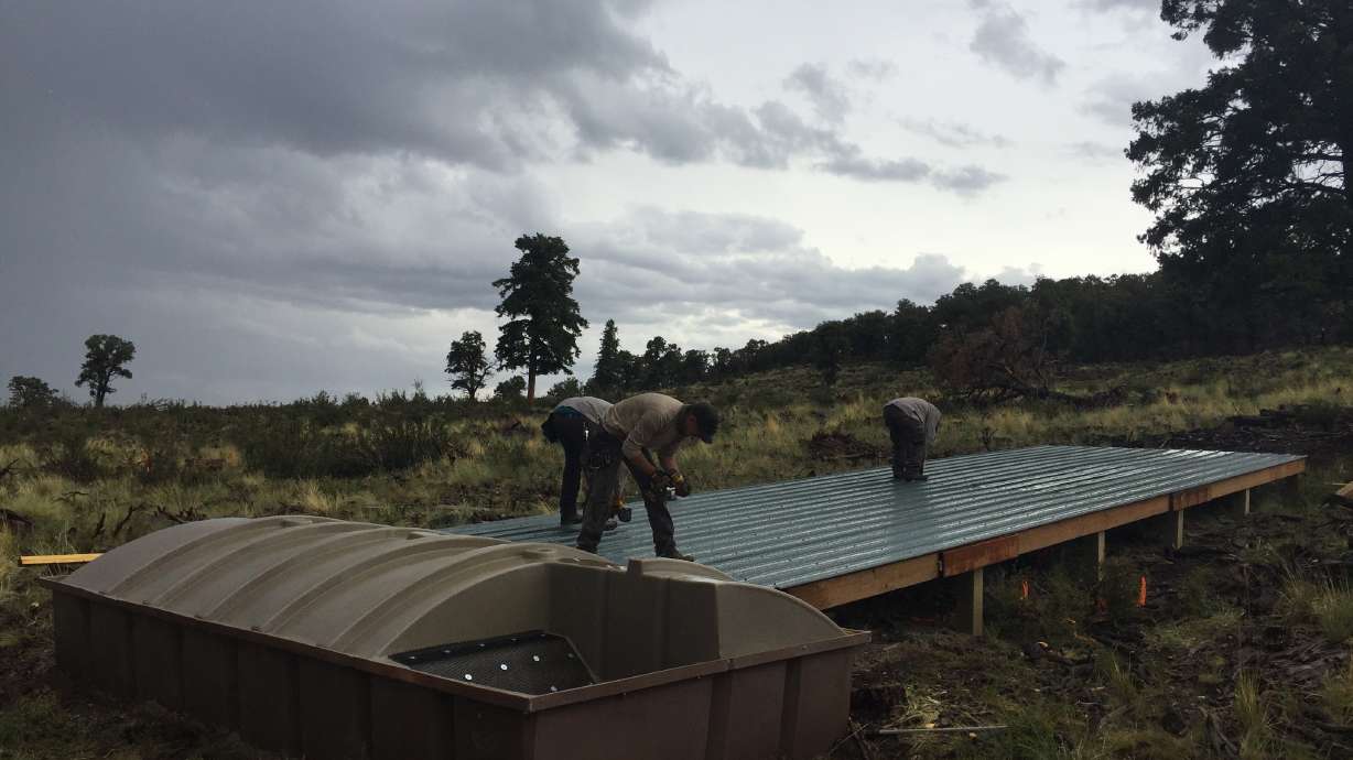 Crews from the Utah Division of Wildlife Resources work to install pieces of a "mega" guzzler in the Book Cliffs range in eastern Utah on July 12, 2021. The 7,200-square-foot guzzler will hold water collected from rain and snow for animals to drink.