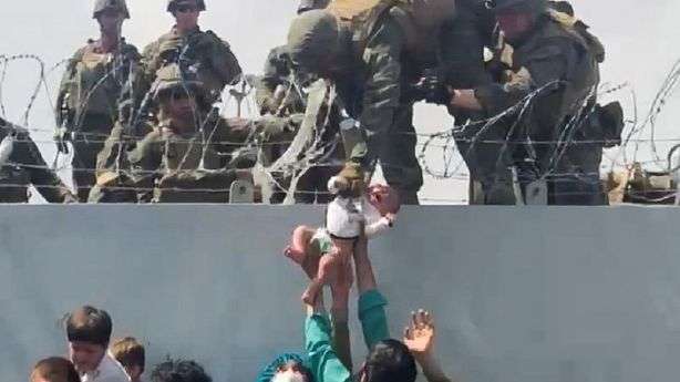 A baby is handed over to the American army over the perimeter wall of the airport for it to be evacuated, in Kabul, Afghanistan, on Thursday.