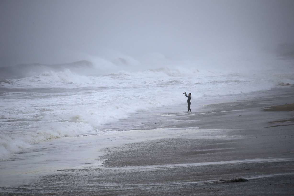 Matt Prue, from Stonington, Conn., takes photos of the waves as Tropical Storm Henri approaches Westerly, R.I., Sunday.