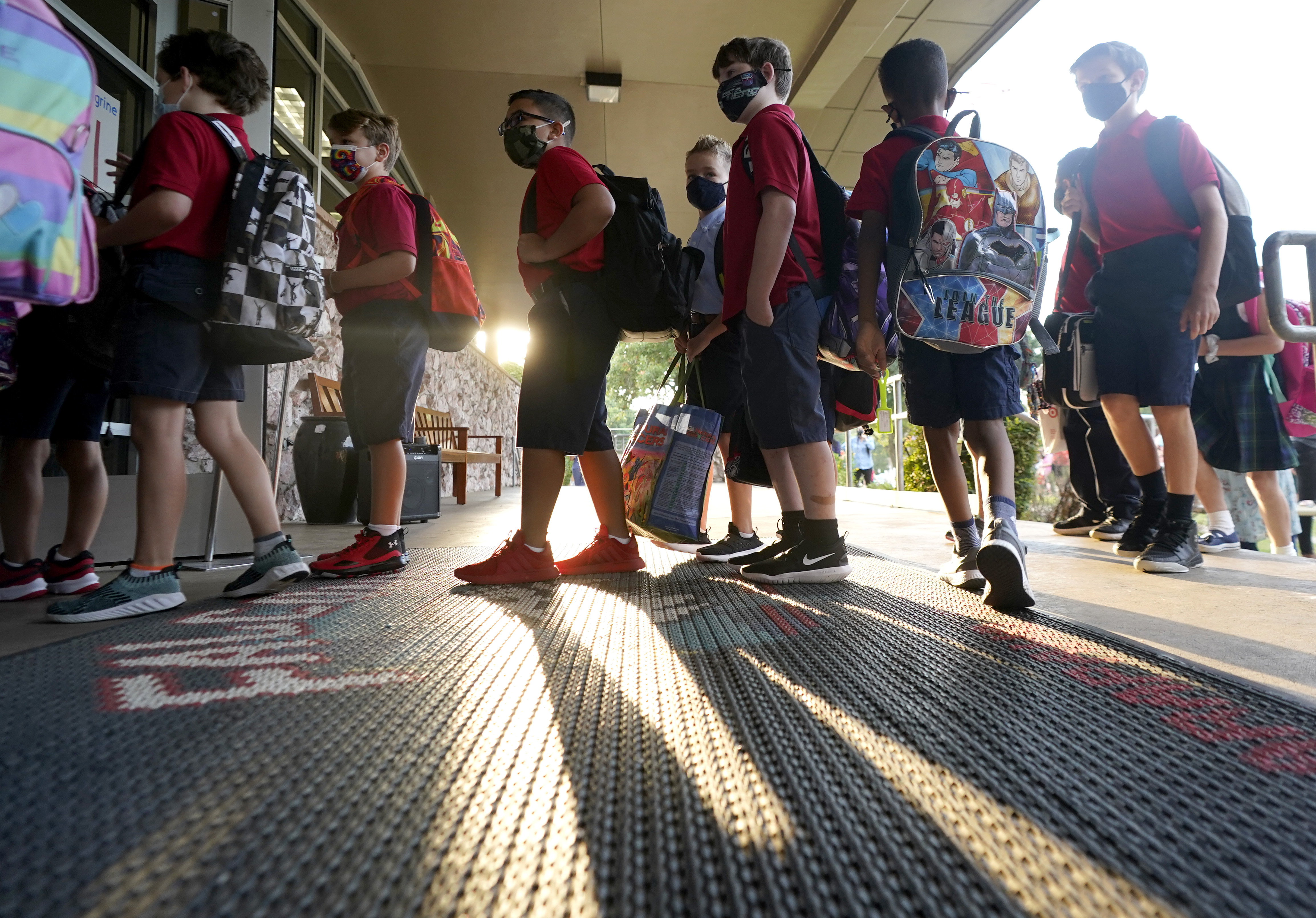Wearing masks to prevent the spread of COVID-19, elementary school students line up to enter school for the first day of classes in Richardson, Texas, on Aug. 17. As COVID-19 cases surge, a majority of Americans say they support mask mandates in K-12 schools.