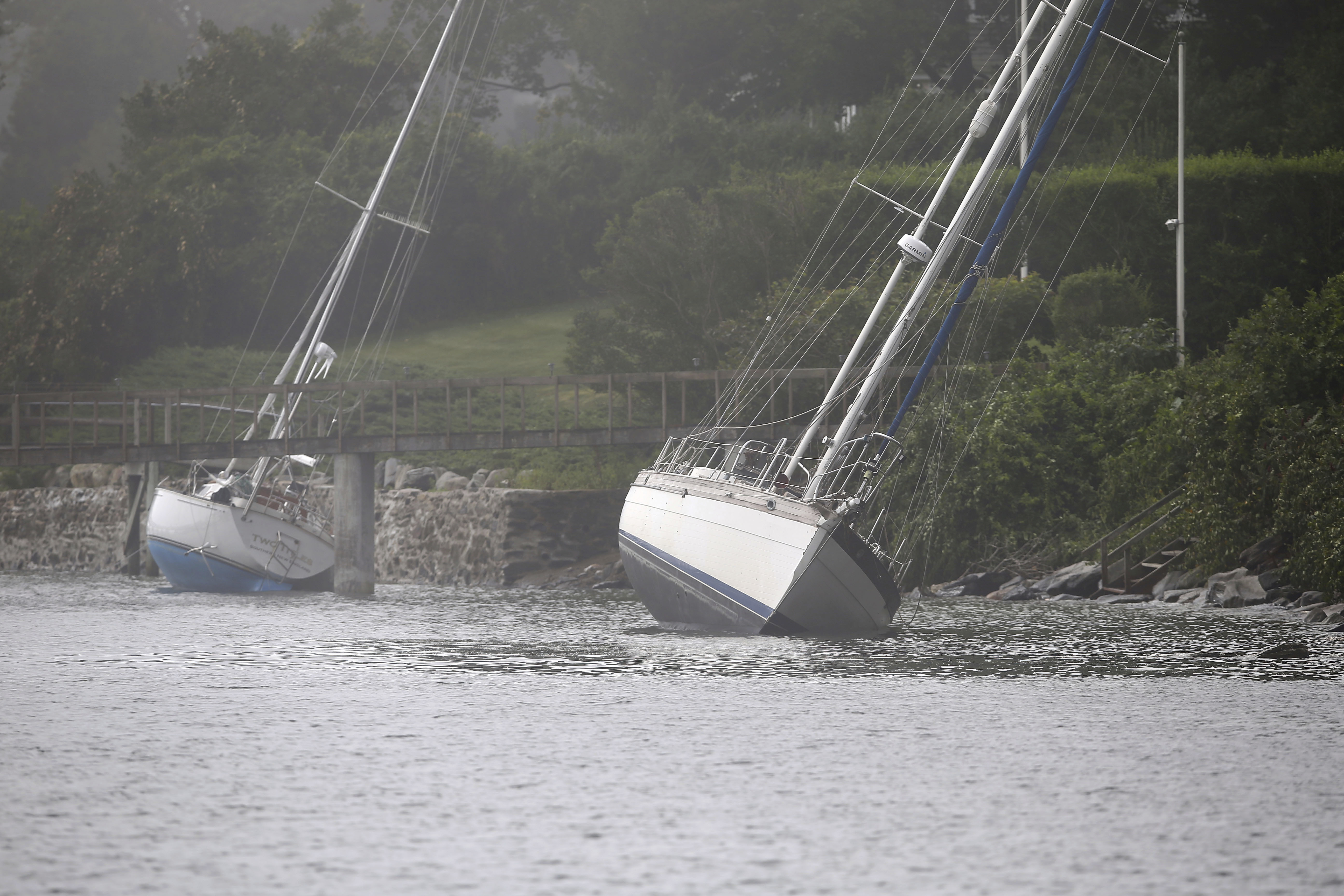 Two sailboats that came loose from their moorings and ran aground during Tropical Storm Henri, still sit on the rocks in Jamestown, R.I., Monday.
