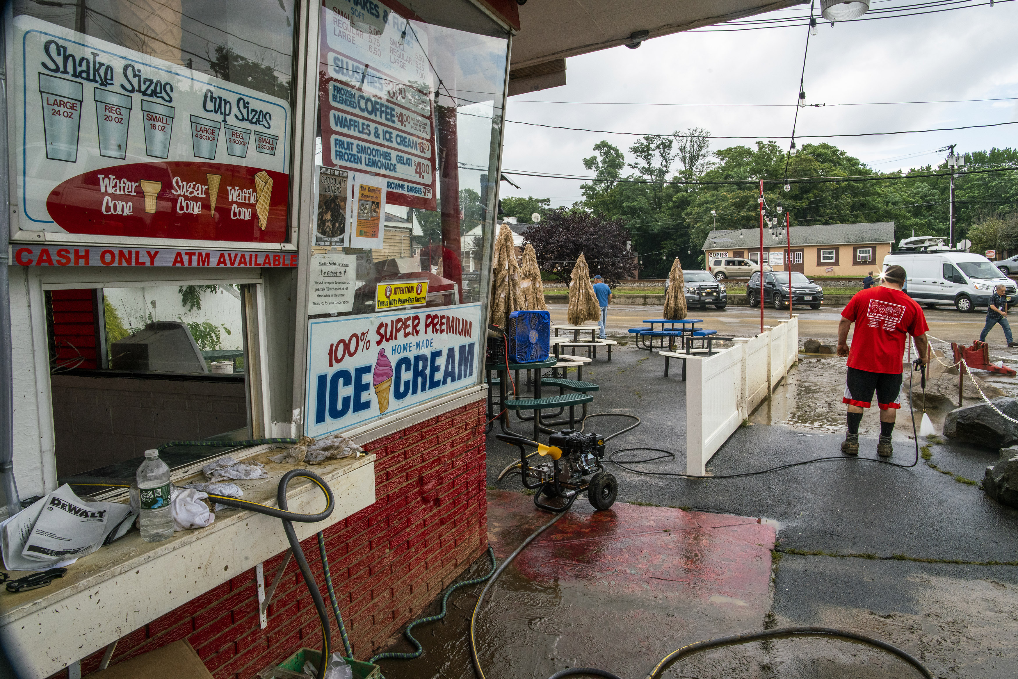 A worker cleans the outside area of Four Boys Ice Cream store during the passing of Tropical Storm Henri in Jamesburg, N.J., Monday.