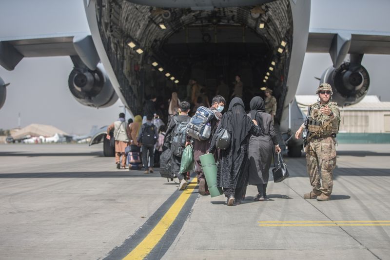 Families begin to board a U.S. Air Force C-17 Globemaster III transport plane during an evacuation at Hamid Karzai International Airport, Afghanistan, on Tuesday.