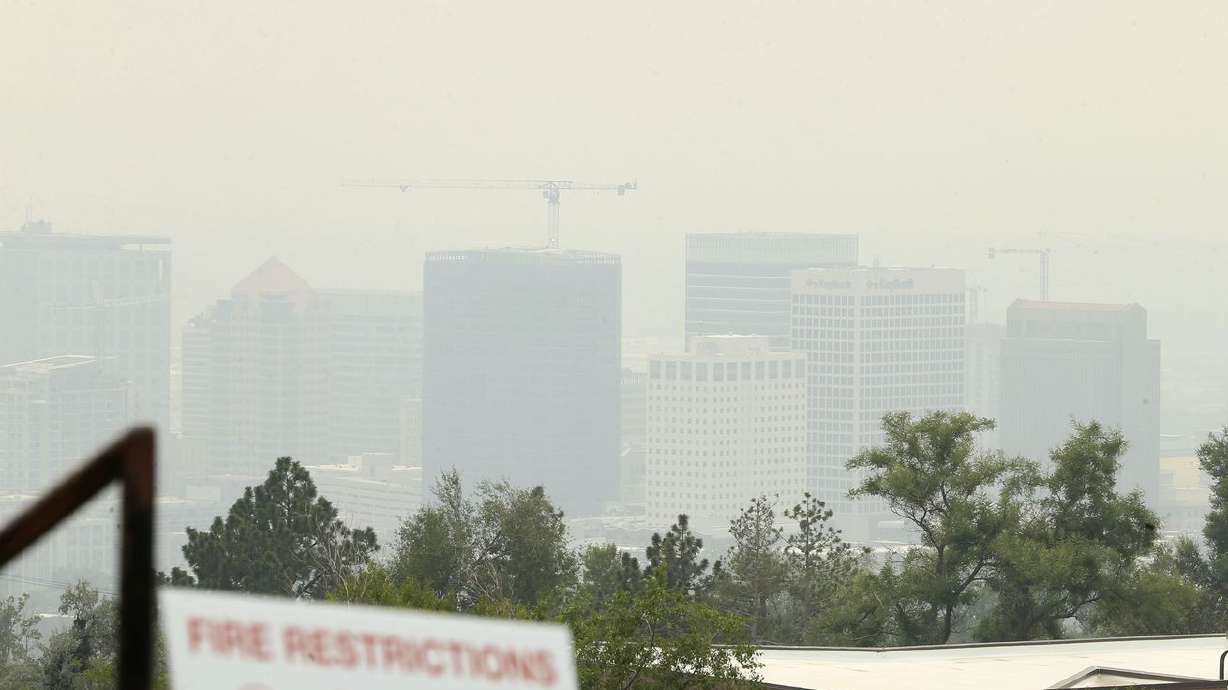 A fire restrictions warning sign is posted in the Avenues while the view of Salt Lake City is obscured by smoke from the California and Oregon wildfires on Friday, Aug. 6, 2021. Wildfires from the West have produced huge columns of smoke that have drifted as far east as New York, creating some of the worst air quality that state has seen in 15 years.