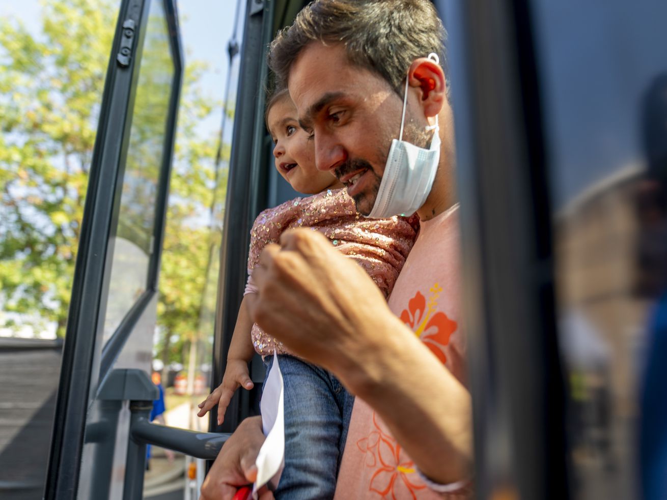 An Afghan man carries a girl as he and other refugees arrive at a processing center in Chantilly, Va., on Monday after arriving on a flight at Dulles International Airport. 
