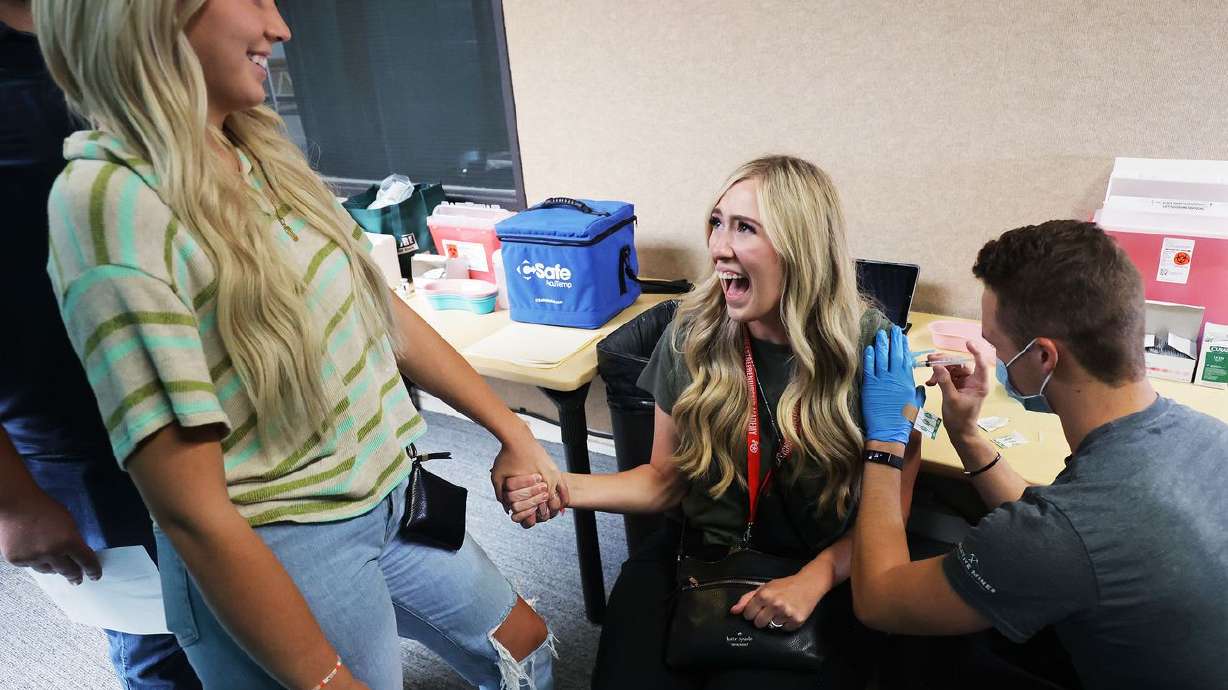 Utah Valley University graduate Lauren Long, right,
holds the hand of her sister, freshman student Amanda Schneck, as she
receives a COVID-19 vaccination at the university in Orem on
Thursday.