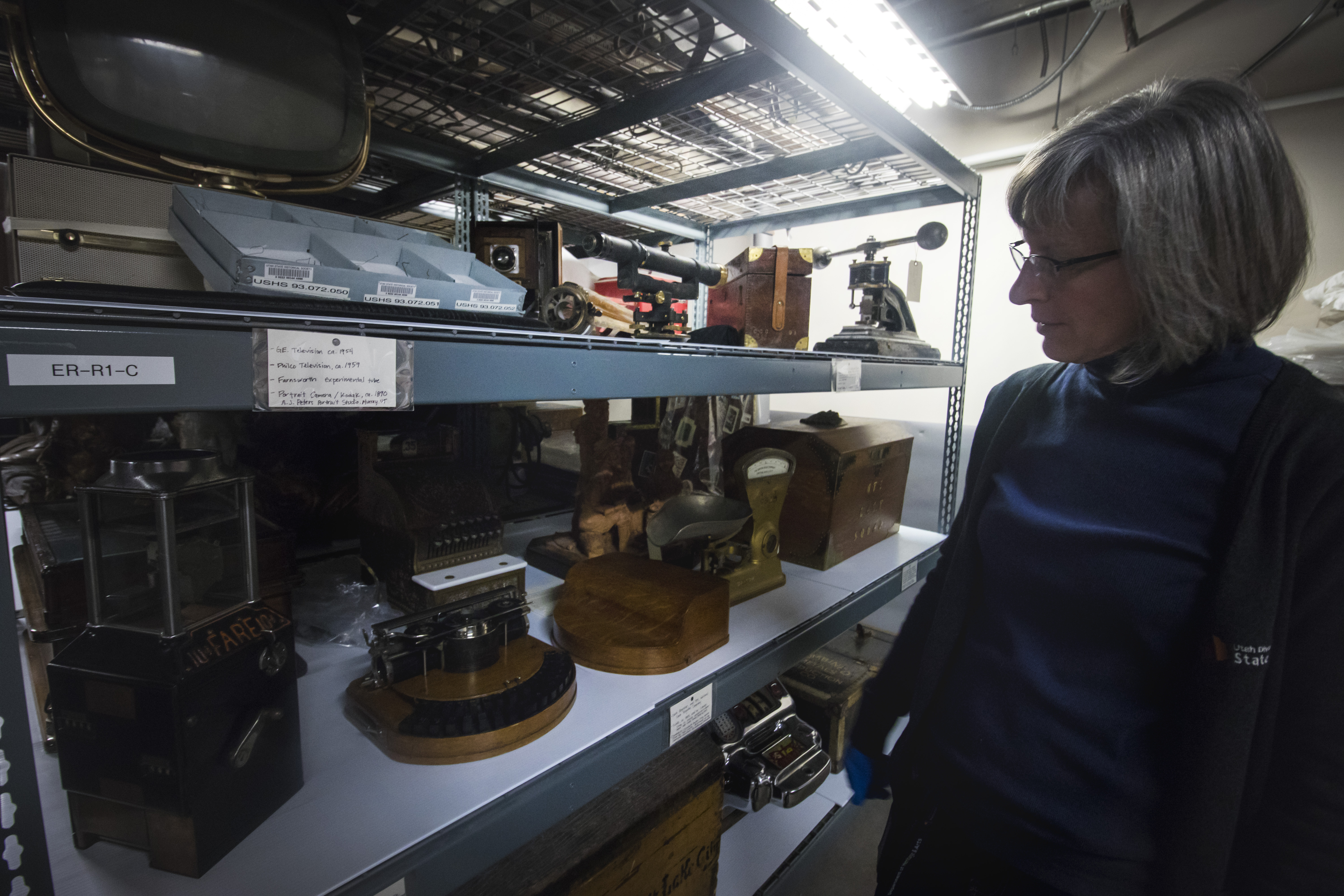 Michele Elnicky, collection specialist for Utah Division of State History, looks at a shelf holding Civilian Conservation Corps equipment, small television tubes donated by television pioneer Philo Farnsworth’s wife and other historic items in 2018. The collection will be moved out of the Rio Grande Depot later this year before the building is retrofitted.