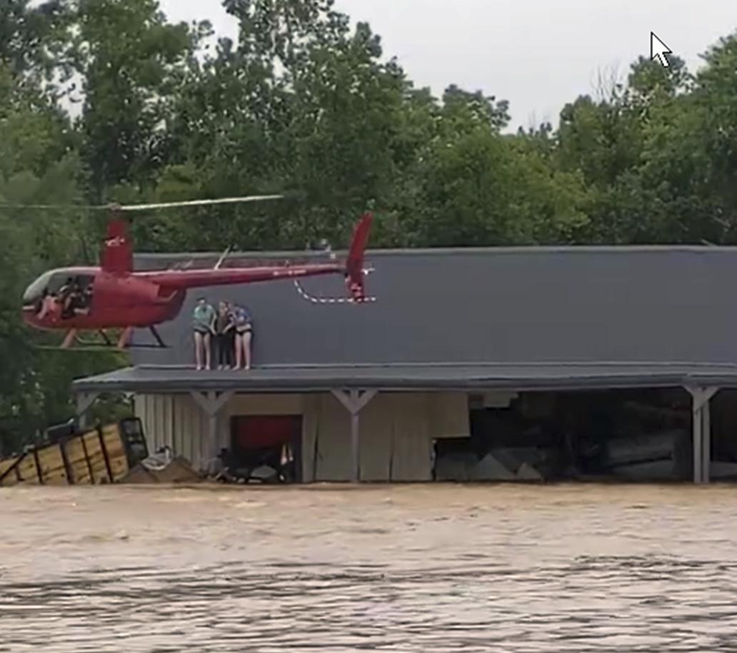 This image from video provided by Jeani Rice-Cranford shows Nashville-based helicopter pilot Joel Boyers rescuing people from a rooftop on Aug. 21 in Waverly, Tenn. Boyers, who co-owns Helistar Aviation, said he ended up rescuing 17 people that day.