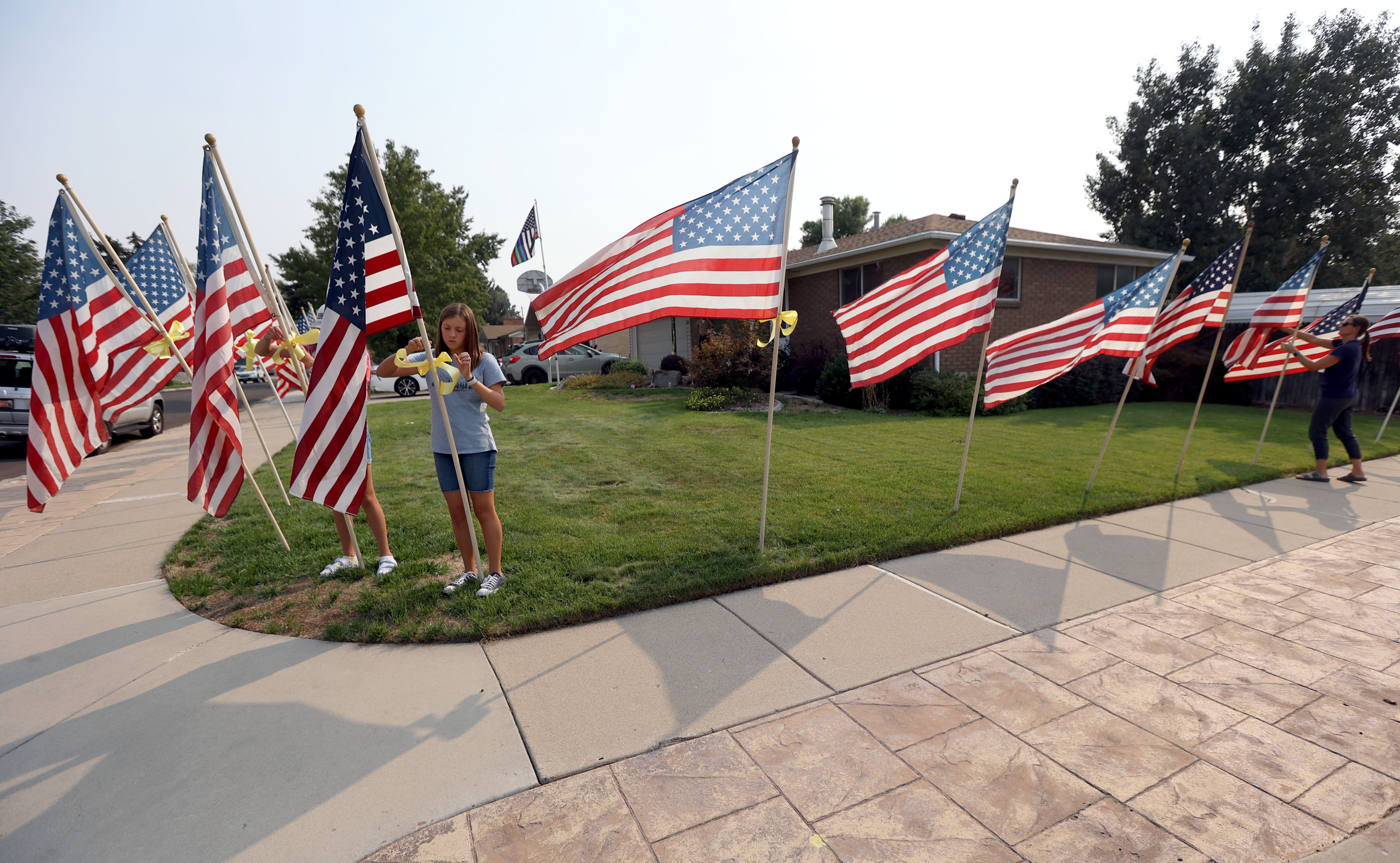 Cora McIllece and Lena McIllece, friends and neighbors, put up flags around house belonging to the father of U.S. Marine Staff Sgt. Darin Taylor Hoover Jr. in Sandy on Friday. Hoover Jr. was killed in the suicide bombing at the Kabul Airport in Afghanistan.