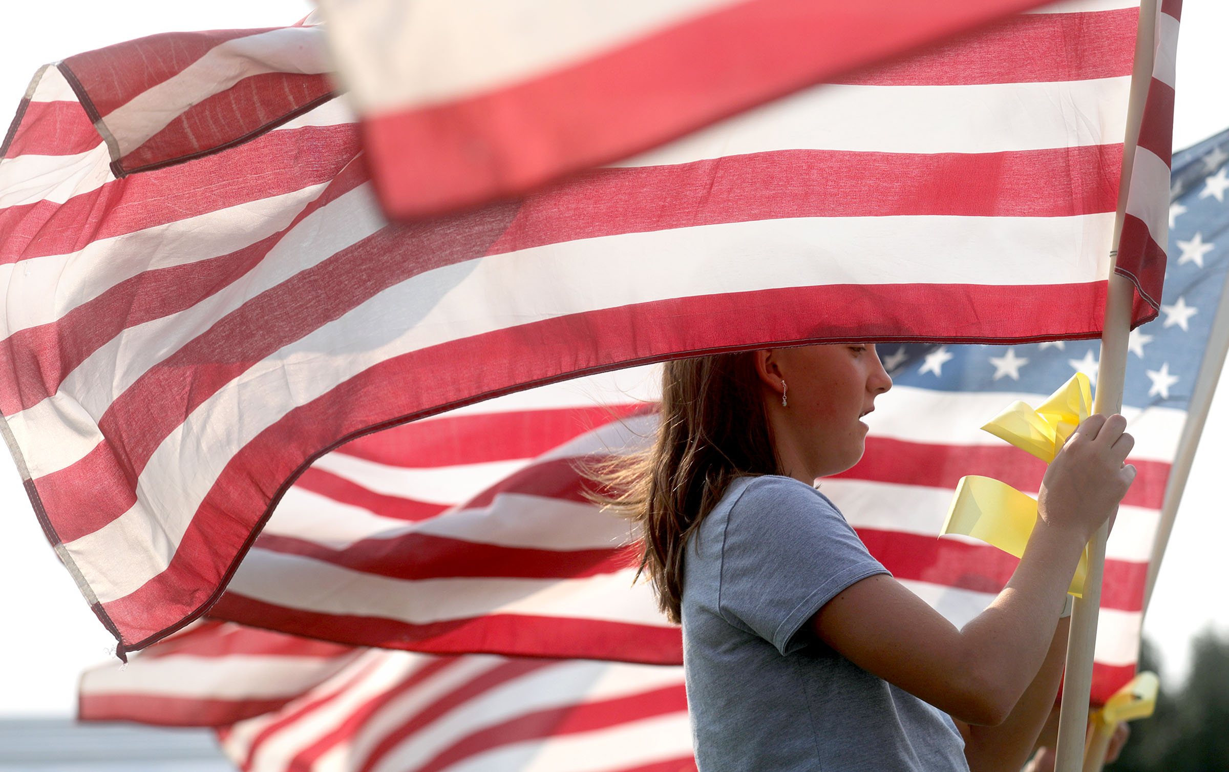 Neighbor Cora McIllece puts up flags around the house belonging to the father of U.S. Marine Staff Sgt. Darin Taylor Hoover Jr. in Sandy on Friday. Hoover Jr. was killed in the suicide bombing at the Kabul Airport in Afghanistan.