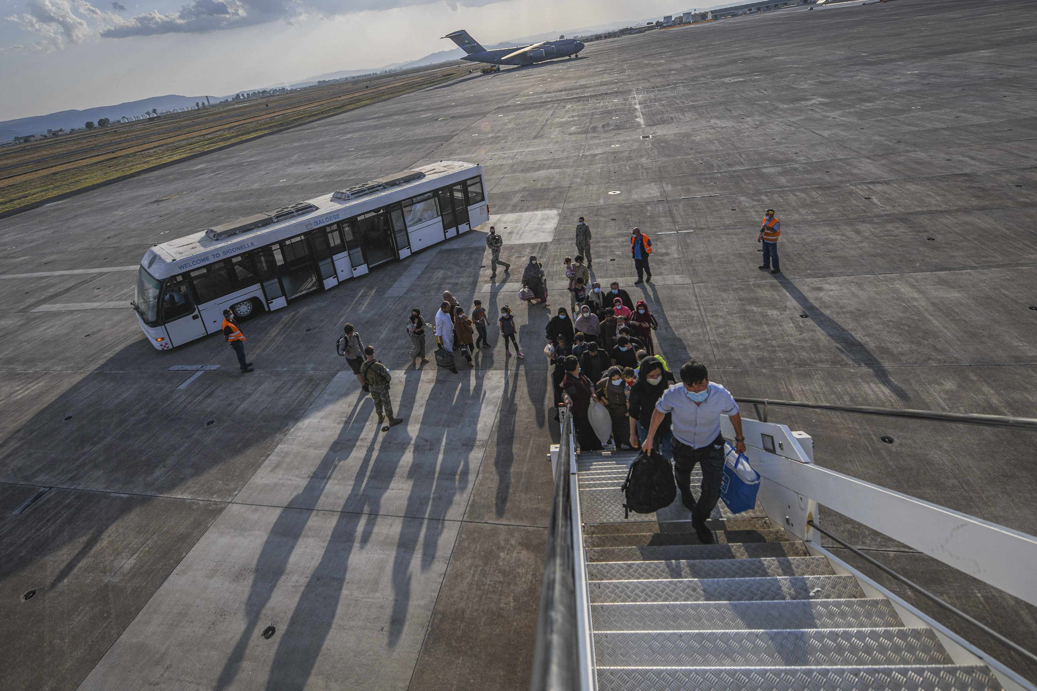 In this image provided by the U.S. Navy, evacuees from Afghanistan board a Boeing 777 bound for the United States from Naval Air Station Sigonella, Italy, Saturday.