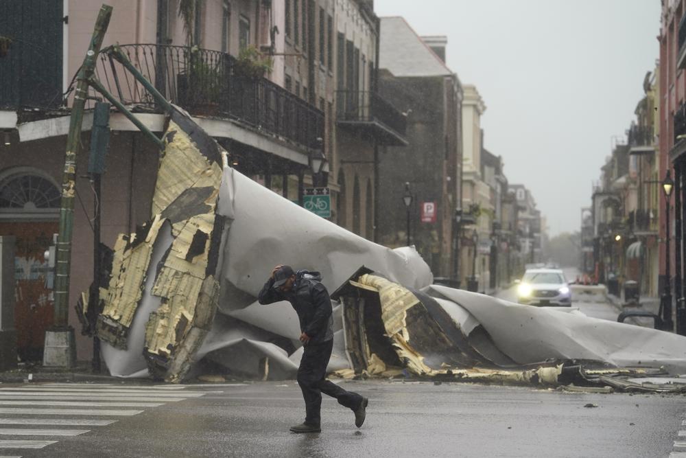 A man passes by a section of roof that was blown off of a building in the French Quarter by Hurricane Ida winds, Sunday, in New Orleans.