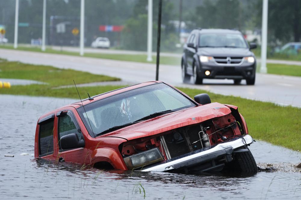 An abandoned vehicle is half submerged in a ditch next to a near flooded highway as the outer bands of Hurricane Ida arrive Sunday, in Bay Saint Louis, Miss.