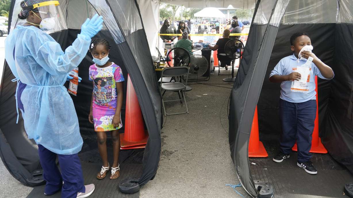 Wenderson Cerisene, 7, right, and his sister Dorah, 9, wait to get tested for COVID-19, on Tuesday in North Miami, Florida. Florida schools are seeing a rise in COVID-19 cases forcing of students and teachers to quarantine.