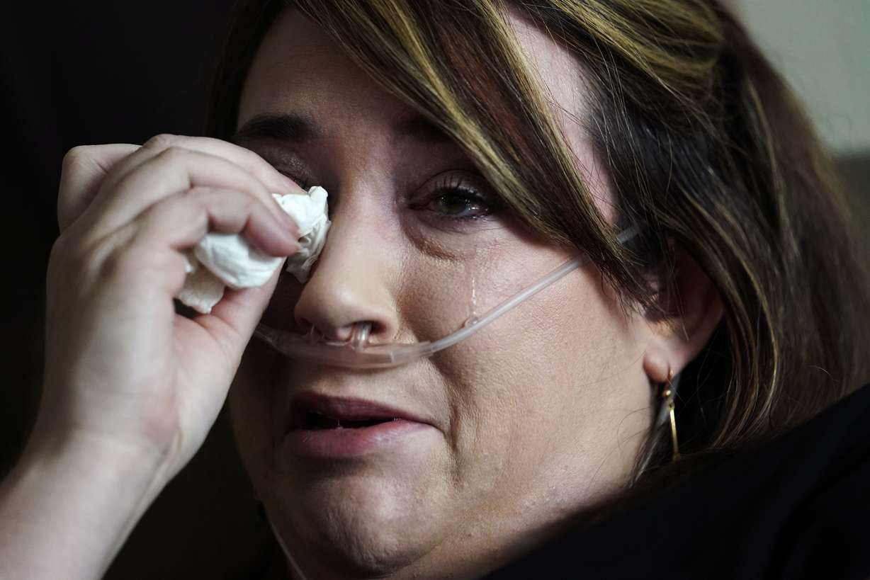 Lauren Debroeck, who is on oxygen as she recovers from COVID-19, cries as she talks about her family, at the bedside of her husband, Michael, who also contracted COVID-19 and is being kept alive with the help of an oxygenation machine at the Willis-Knighton Medical Center in Shreveport, Louisiana, on Wednesday, Aug. 18.