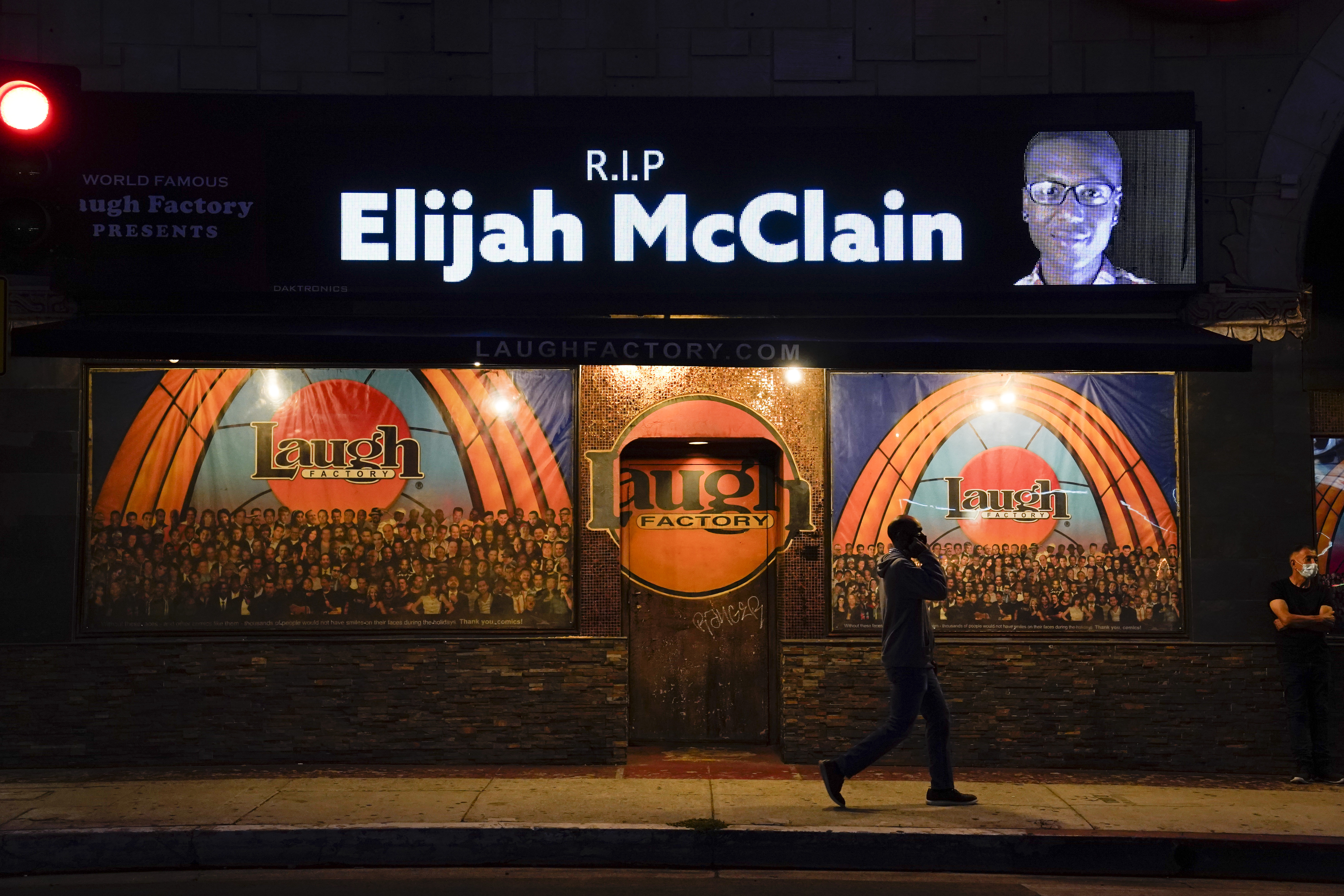 A man walks past a display showing an image of Elijah McClain outside Laugh Factory during a candlelight vigil for McClain in Los Angeles, Aug. 24, 2020. Colorado’s attorney general plans to make an announcement Wednesday about the grand jury investigation into the death of McClain, a Black man who was put in a chokehold and injected with a powerful sedative two years ago in suburban Denver.