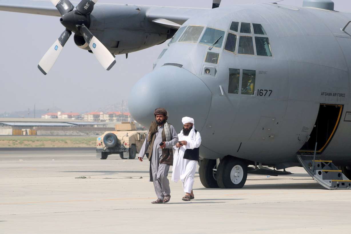 Taliban walk in front of a military airplane on Tuesday, a day after the U.S. troops withdrawal from Hamid Karzai International Airport in Kabul, Afghanistan.