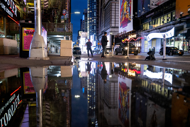 The lights of Times Square in New York are reflected in standing water Thursday.