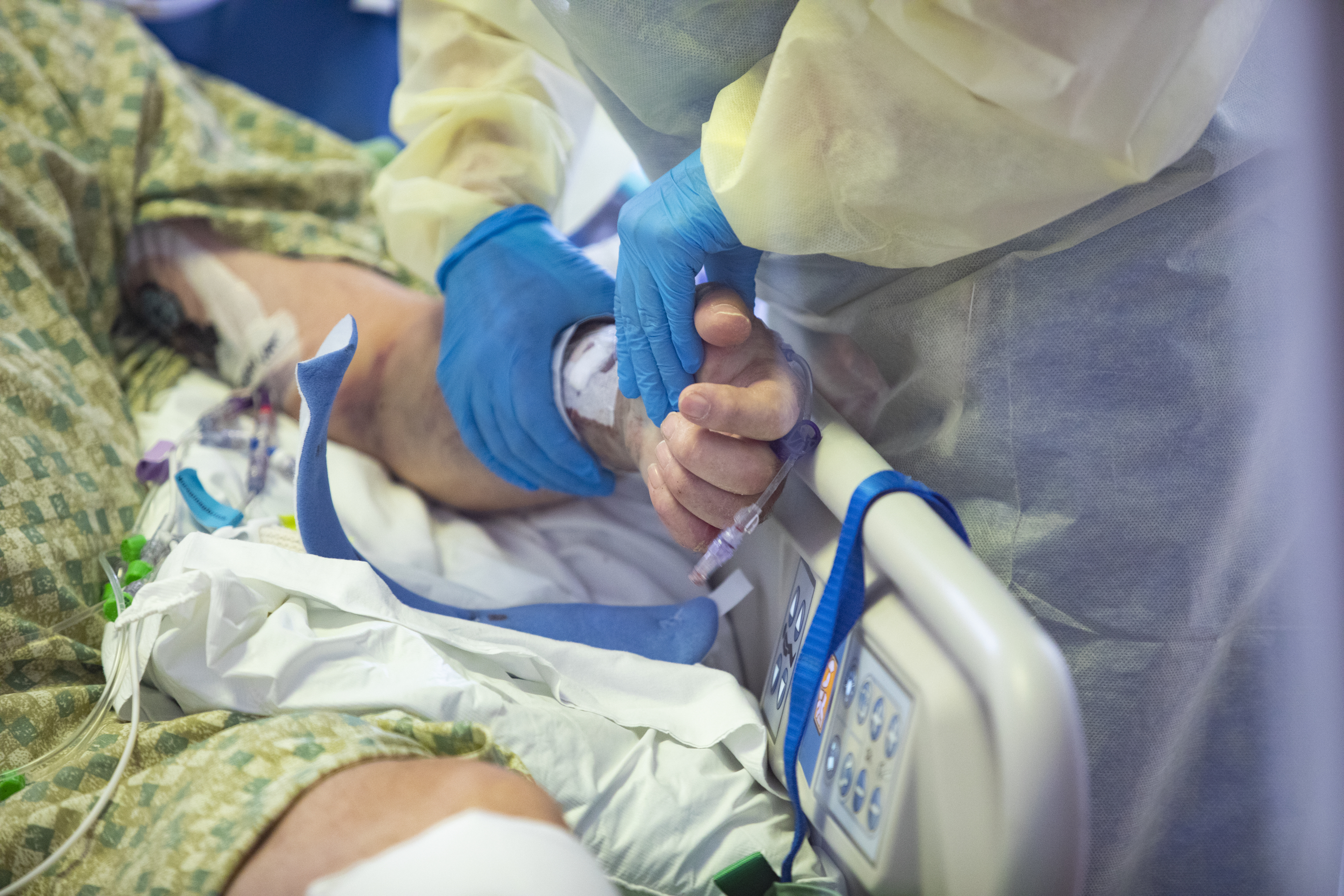A registered nurse holds the hand of a COVID-19 patient in the medical intensive care unit at St. Luke's Boise Medical Center in Boise, Idaho, on Tuesday, Aug. 31. More than half of the patients in the ICU are COVID-19 positive, none of which are vaccinated.