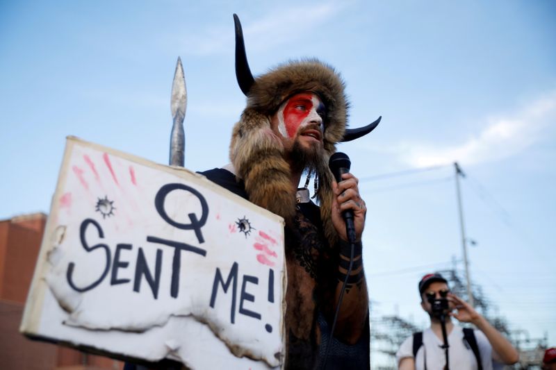 Jacob Chansley, holding a sign referencing QAnon, speaks as supporters of President Donald Trump gather to protest about the early results of the 2020 presidential election, in front of the Maricopa County Tabulation and Election Center in Phoenix, Arizona Nov. 5, 2020. He pleaded guilty to taking part in the Jan. 6 attack at the Capitol.