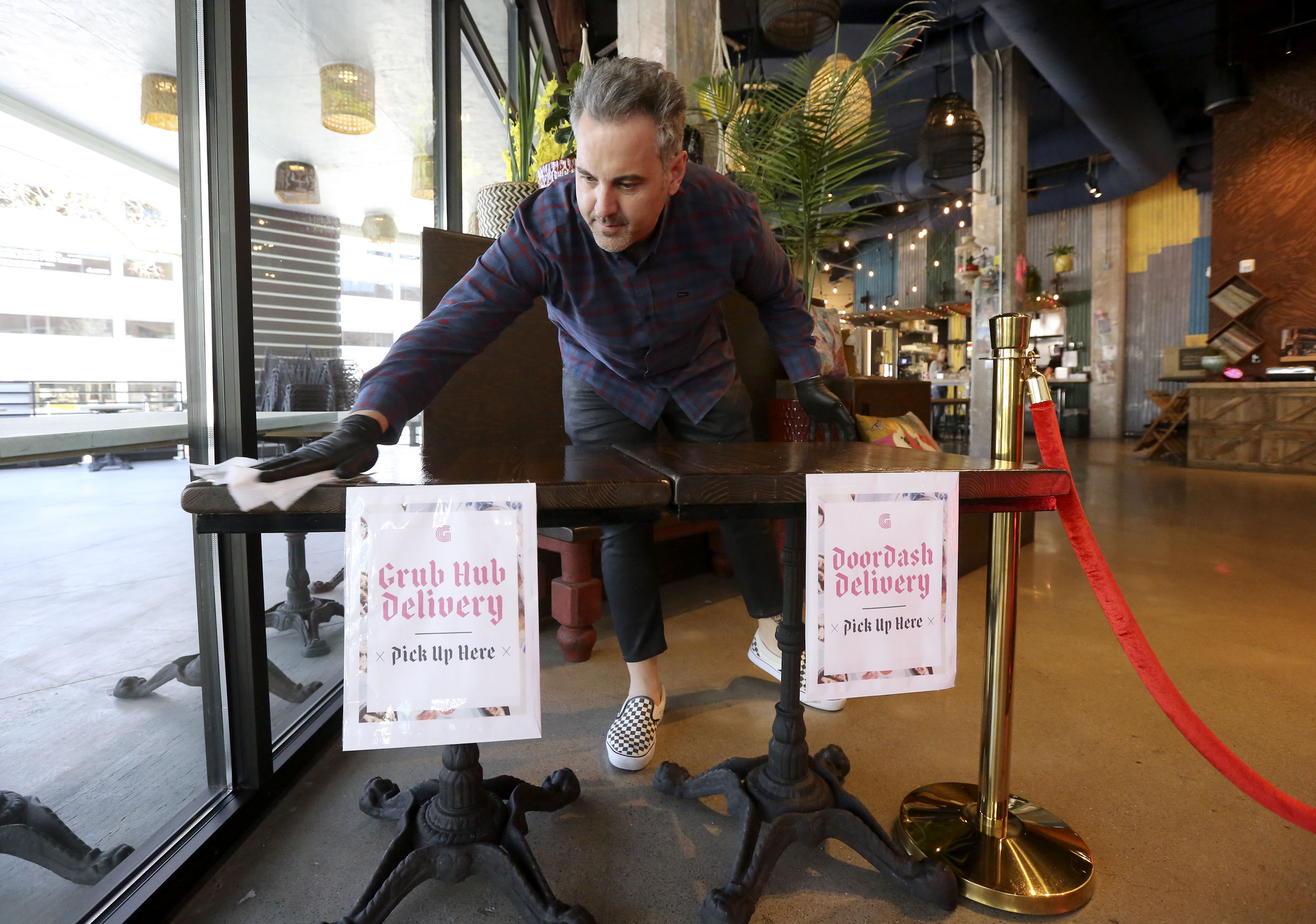 Michael McHenry, founder of The McHenry Group and restauranteur behind Dirty Bird Fried Chxx in Provo, wipes down a table where food delivery orders are picked up with a sanitizing wipe at Ginger Street in Salt Lake City on April 3, 2020. The McHenry Group announced Friday that Dirty Bird Hot Chxx had been acquired by Wags Capital with plans to open as many as 30 new locations in the next year or so.