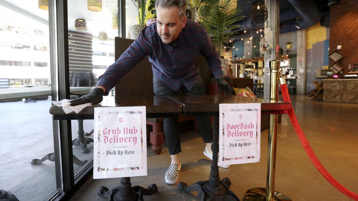 Michael McHenry, founder of The McHenry Group and restauranteur behind Dirty Bird Fried Chxx in Provo, wipes down a table where food delivery orders are picked up with a sanitizing wipe at Ginger Street in Salt Lake City on April 3, 2020. The McHenry Group announced Friday that Dirty Bird Hot Chxx had been acquired by Wags Capital with plans to open as many as 30 new locations in the next year or so.