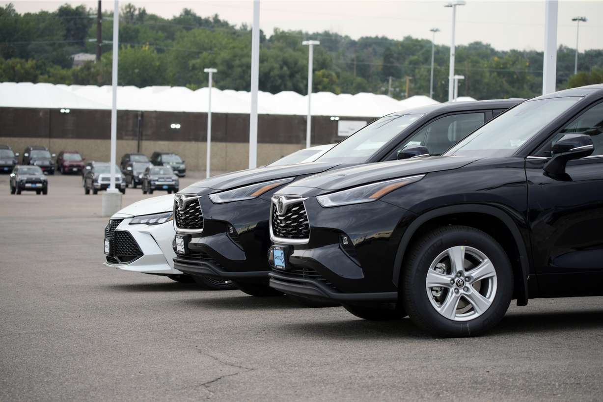 A pair of unsold 2021 Highlander sports utility vehicles and a Camry sedan are parked on the empty storage lot outside a Toyota dealership in Englewood, Colorado on Aug. 29. A global shortage of computer chips has forced automakers to temporarily close factories, limiting production and driving up prices. The coronavirus delta variant is now causing shortages of other parts.