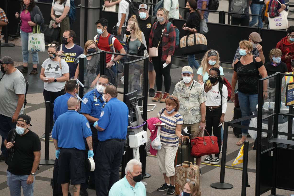 Travelers wear face coverings in the line for the south north security checkpoint in the main terminal of Denver International Airport Tuesday, Aug. 24, in Denver.