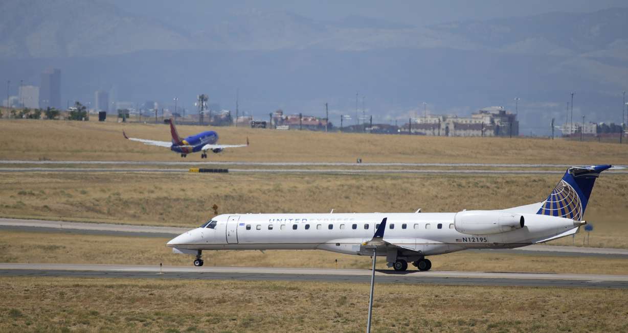A United Express jet taxis down a runway as a Southwest Airlines plane takes off in the background at Denver International Airport, Tuesday, Aug. 24, in Denver.