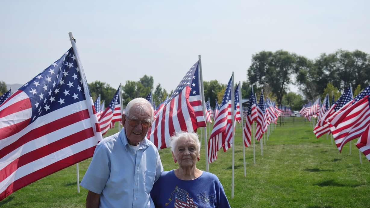 George and Bunny Akins pose in front of a flag display commemorating the 20th anniversary of terrorist attacks on Sept. 11, 2001, at Riverton City Park on Monday.