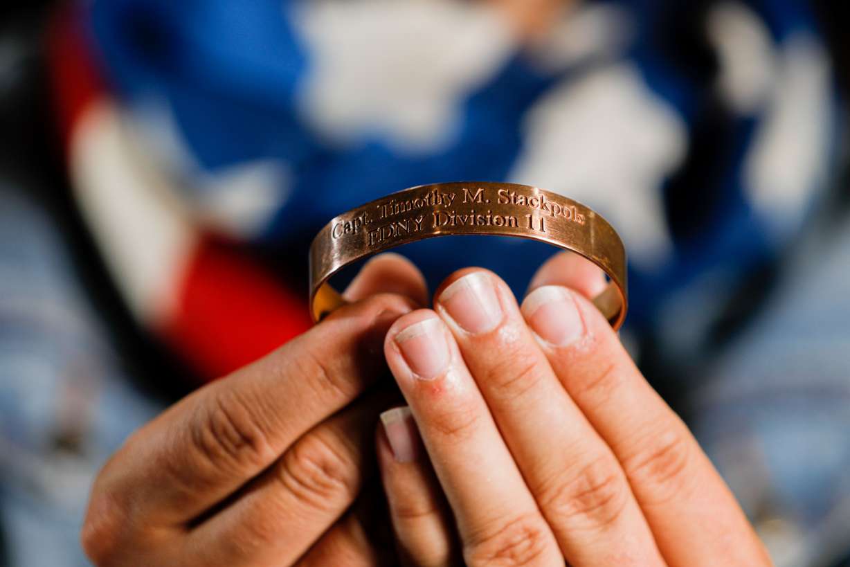 Catherine Raney Norman, Olympic speed skater and Salt Lake City Committee for the Games bid leader, poses for a portrait at Utah Olympic Oval in Kearns on Saturday, Aug. 28, 2021, while holding a bracelet she wore while competing in the 2002 Winter Games bearing the name of a New York City firefighter killed in the 9/11 attacks.