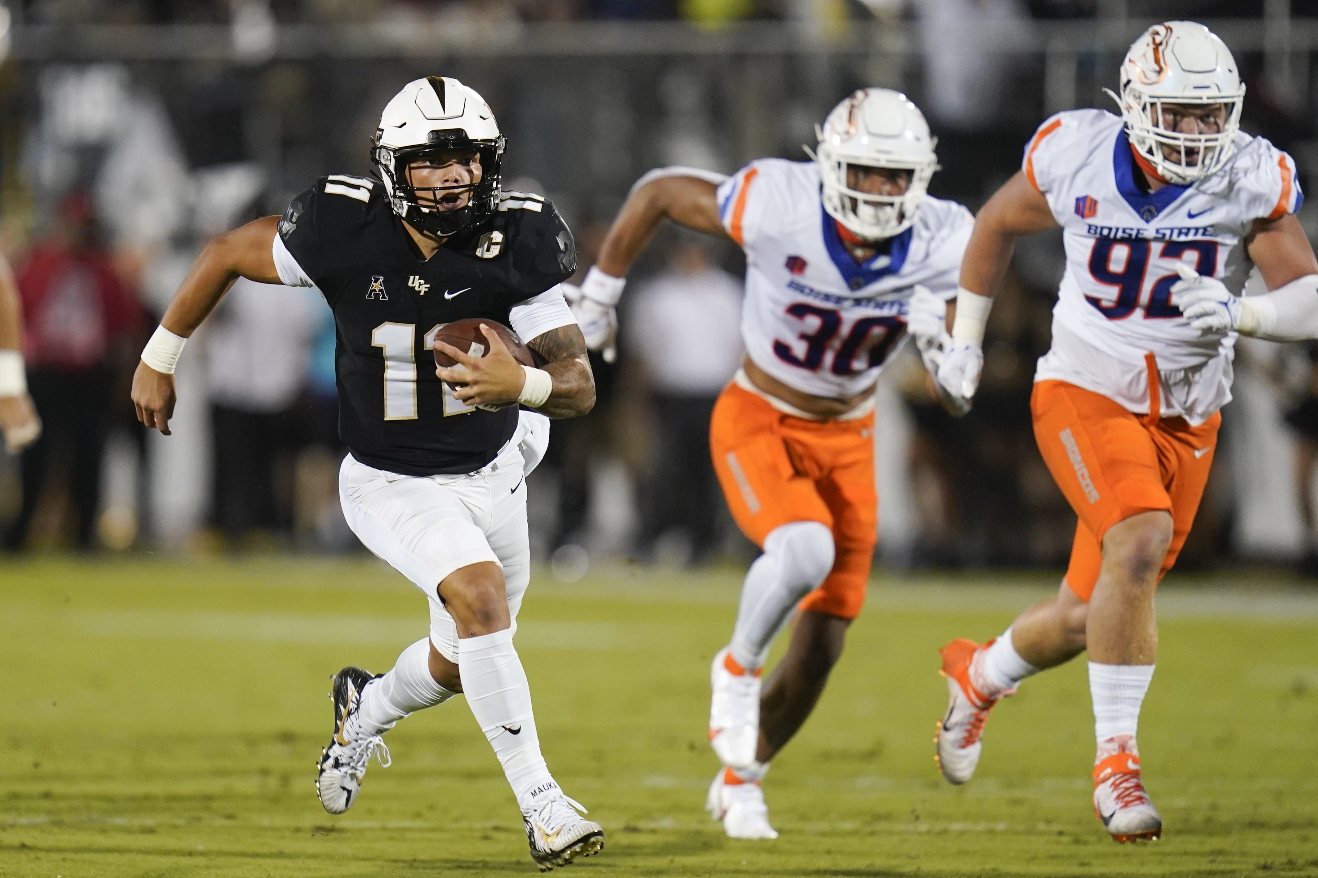 Central Florida quarterback Dillon Gabriel, left, runs for yardage past Boise State defensive end Isaiah Bagnah (30) and defensive tackle Michael Callahan (92) during the first half of an NCAA college football game Thursday, Sept. 2, 2021, in Orlando, Fla.