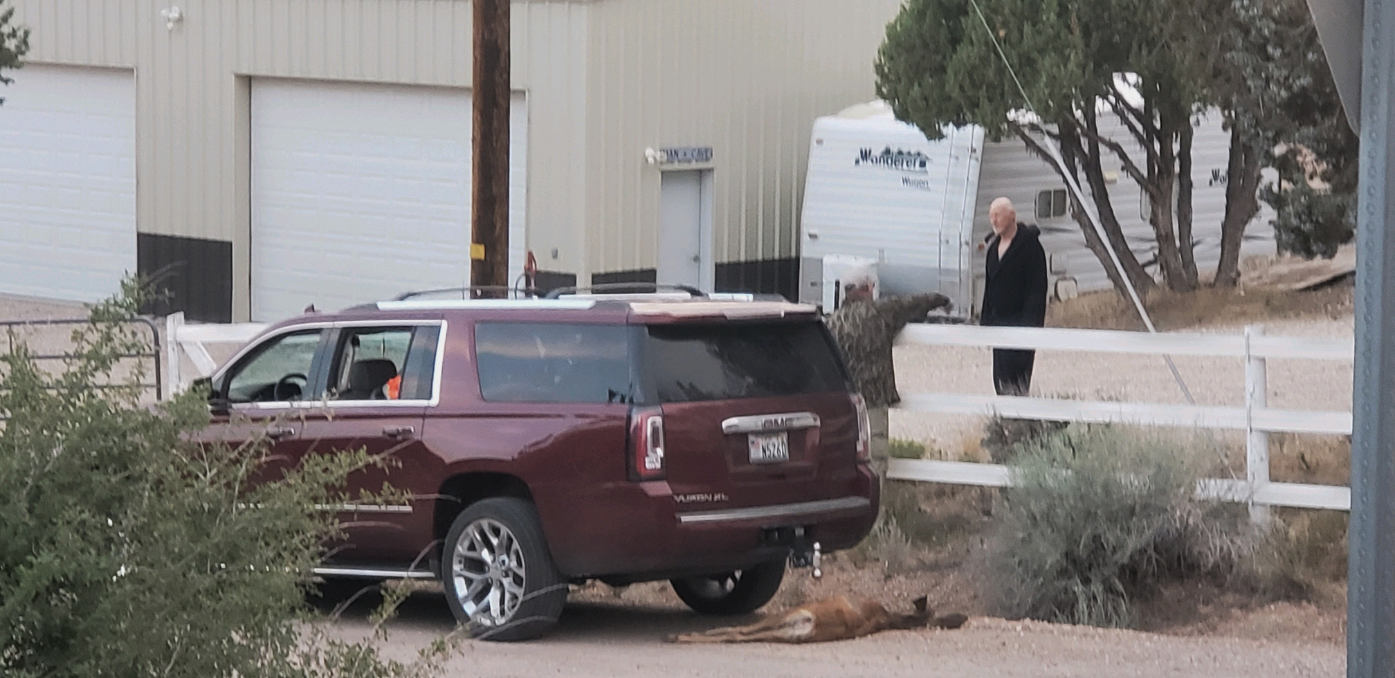 A deer carcass is visible beneath a GMC Yukon SUV as Utah state Rep. Travis Seegmiller, left, speaks with Dr. Kelly Reber, a property owner in rural Washington County, Utah, Aug. 13.