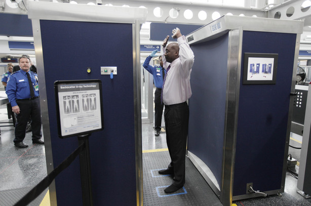 A volunteer passes through the first full body scanner installed at O'Hare International Airport in Chicago on March 15, 2010. The technology produces a cartoon-like outline rather than naked images of passengers by using X-rays.