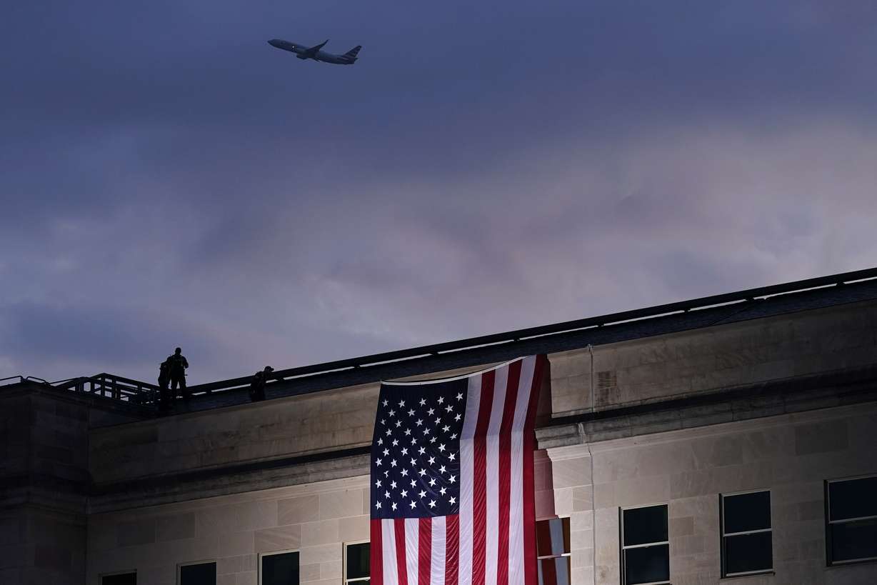 A plane takes off from Washington Reagan National Airport on Friday, Sept. 11, 2020, as a large U.S. flag is unfurled at the Pentagon ahead of ceremonies at the National 9/11 Pentagon Memorial to honor the 184 people killed in the 2001 terrorist attack on the Pentagon, in Washington, on Friday, Sept. 11, 2020.