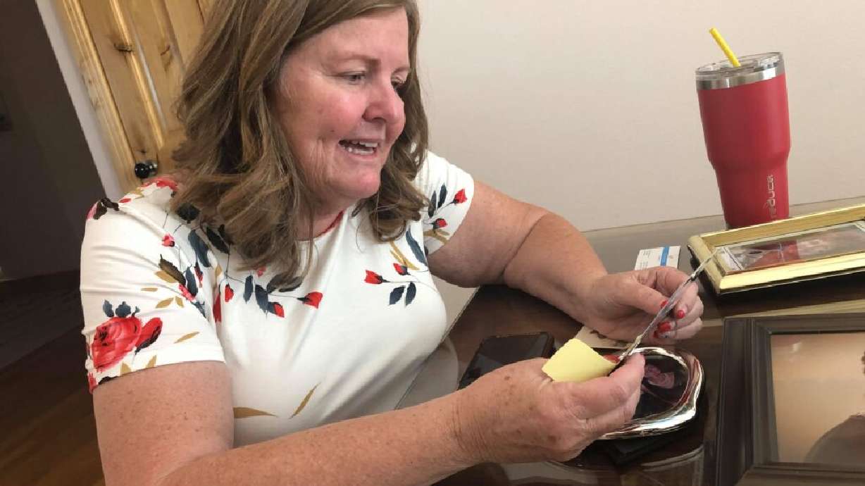 Betsy Bender looks over an old postcard and photographs of her mother and grandmother during an interview in her home, Cedar City Thursday.