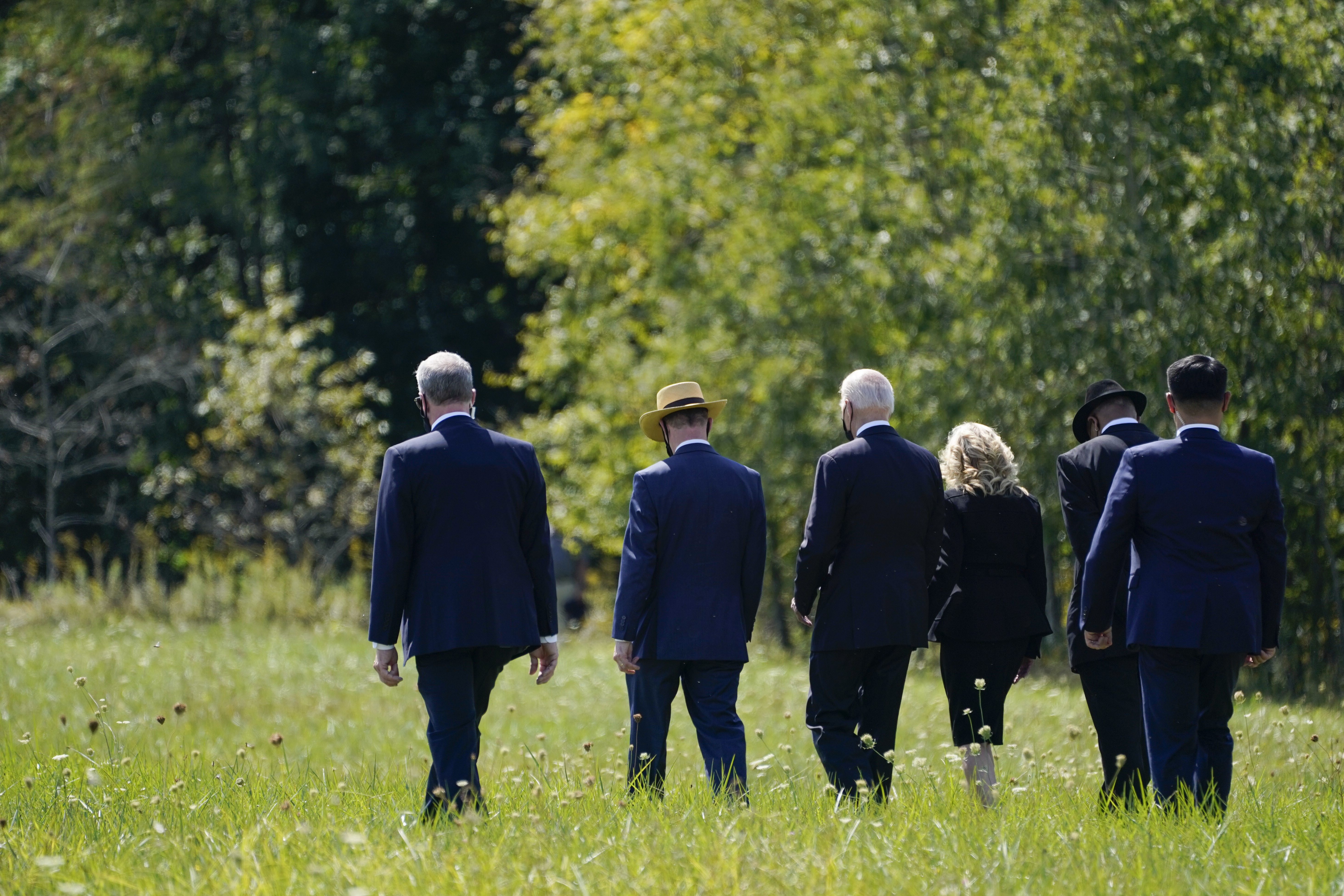 President Joe Biden and first lady Jill Biden walk with Gordon Felt, brother of Edward Porter Felt and President of Families for Flight 93, second from left, and Calvin Wilson the brother-in-law of First Officer LeRoy Homer, a passenger on Flight 93, second from right, to visit a boulder marking the impact site of Flight 93 at the Flight 93 National Memorial in Shanksville, Pa., Saturday.