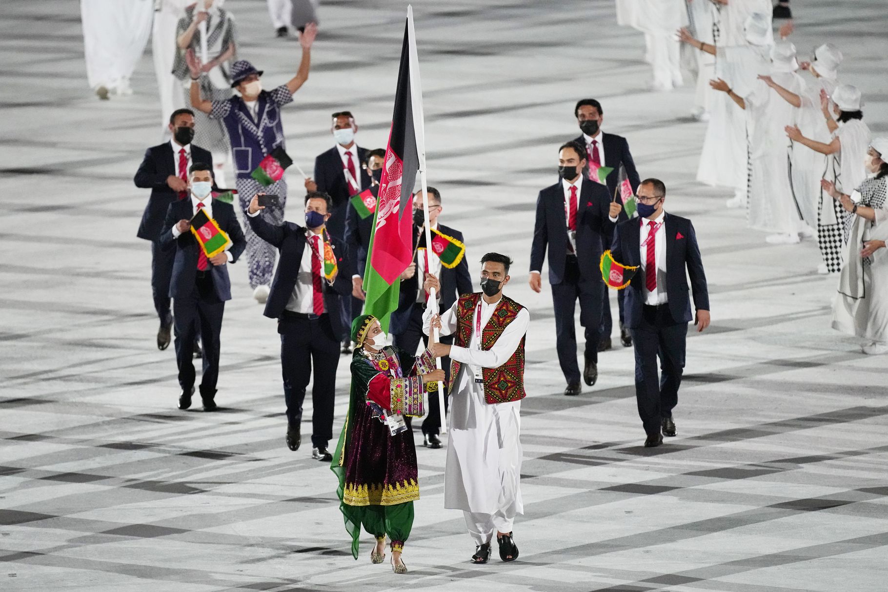 Kimia Yousofi and Farzad Mansouri, of Afghanistan, carry their country’s flag at the 2020 Summer Olympics on Friday, July 23, in Tokyo. None of the athletes from Afghanistan who competed in the Tokyo Summer Games returned to their homeland.