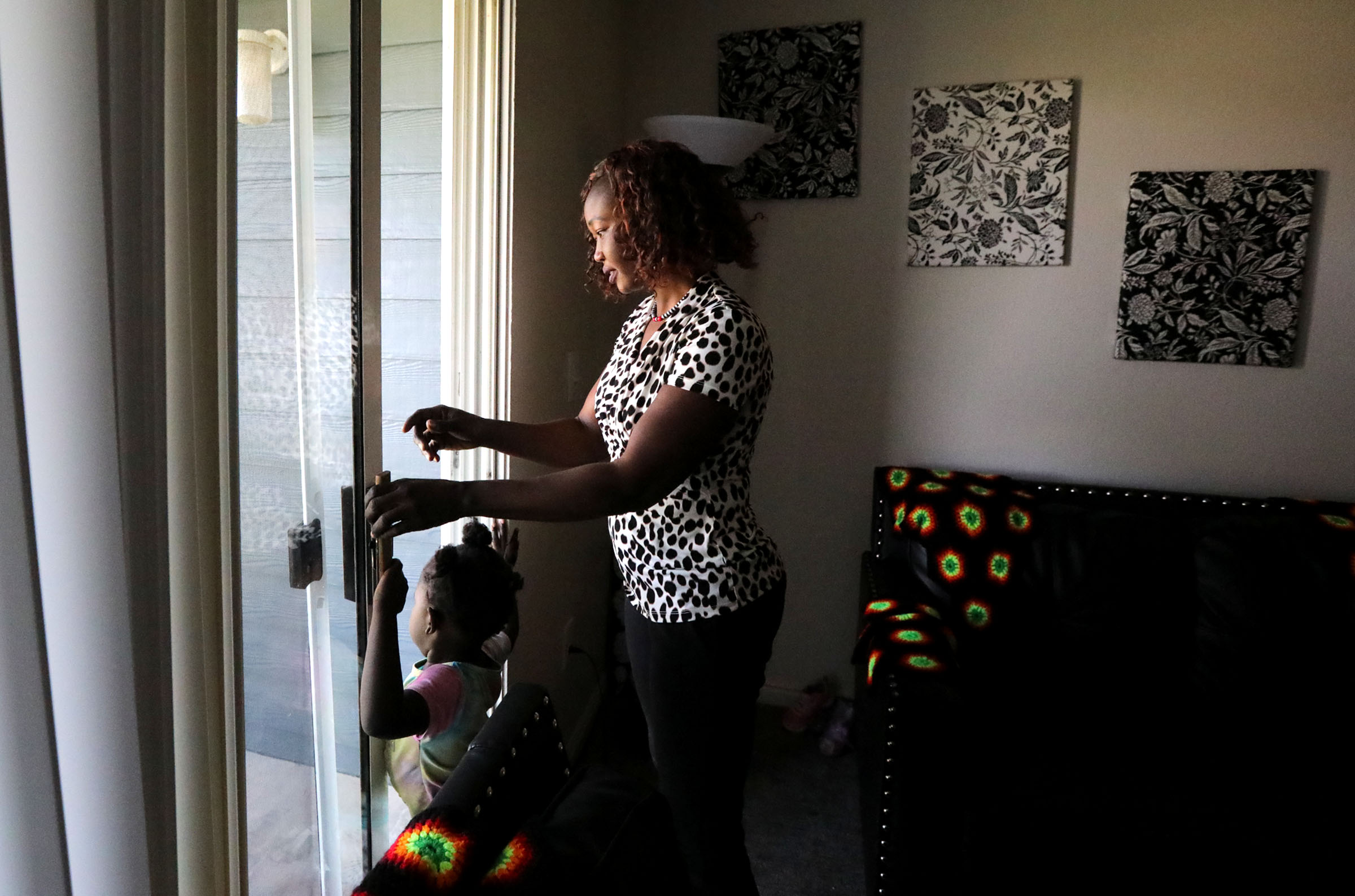 Tabitha Kwayge, a Sudanese refugee, and daughter Siyanna Inna walk out to a deck from their apartment in Midvale on Wednesday. Kwayge is looking for another place for her family to live as the $1,500 monthly rent is too expensive.