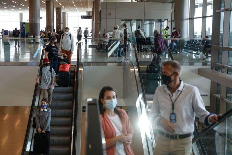 Passengers and airport officials wearing masks ride an
escalator at the Salt Lake City International Airport on Wednesday.
